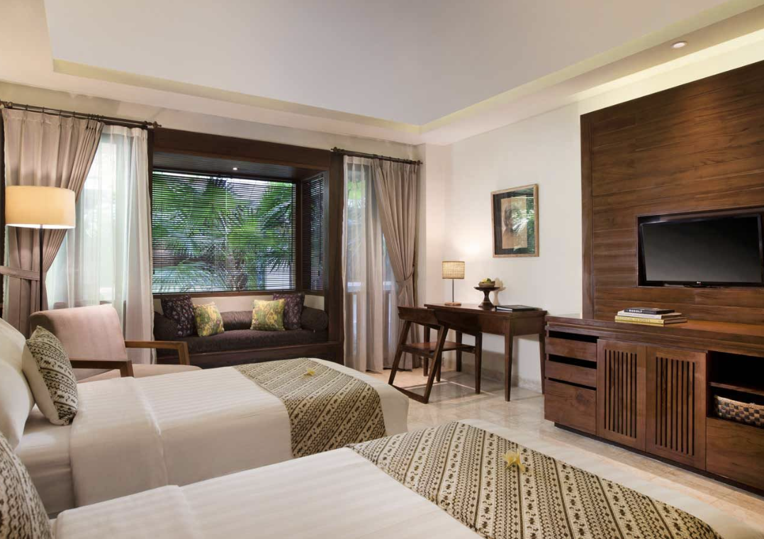 A room with two beds and a televisionDescription automatically generated